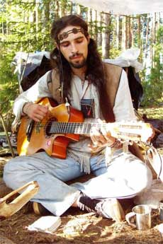 man strumming guitar in clothing typical of hippies